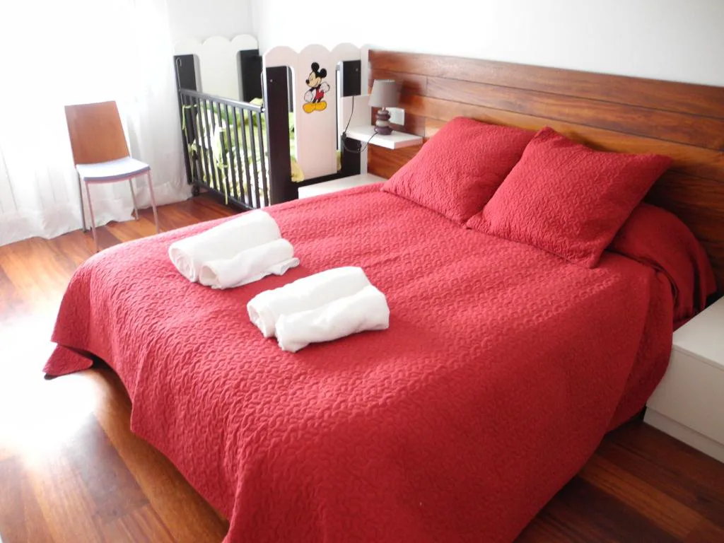 Dormitorio con colcha roja y cabecero blanco