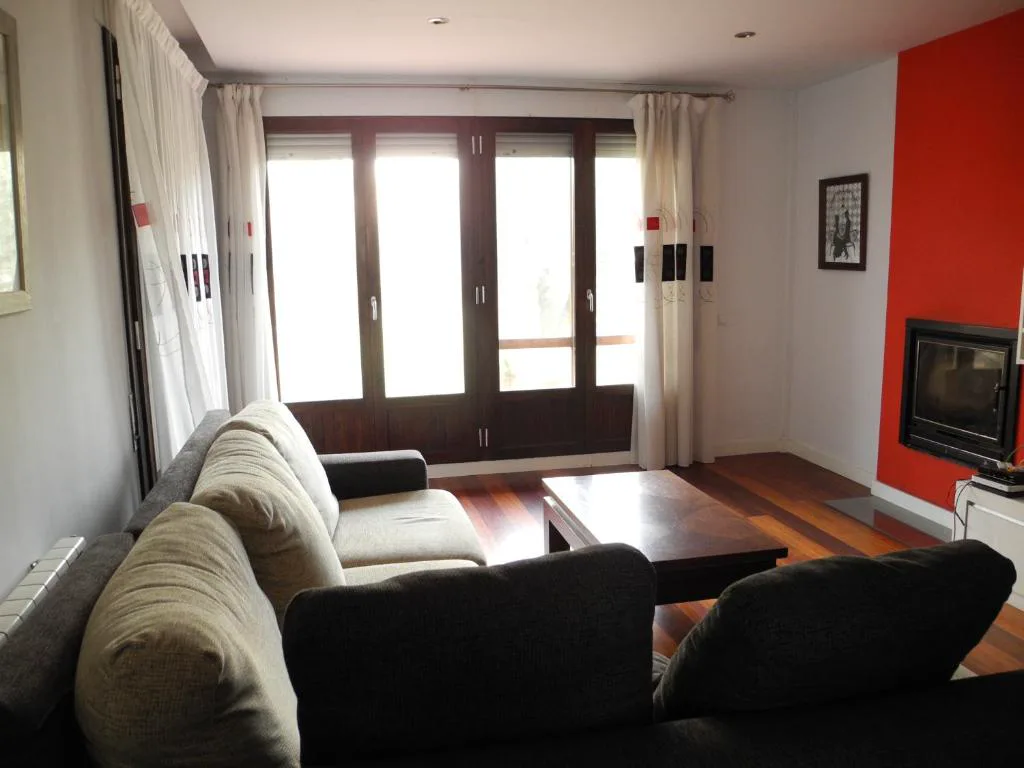 Salón con sofá negro y ventanales