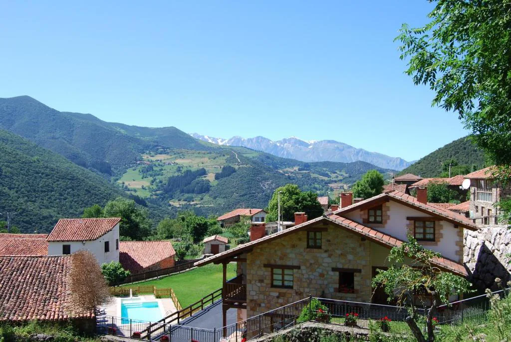 Valle con casas de tejado rojo y montañas al fondo