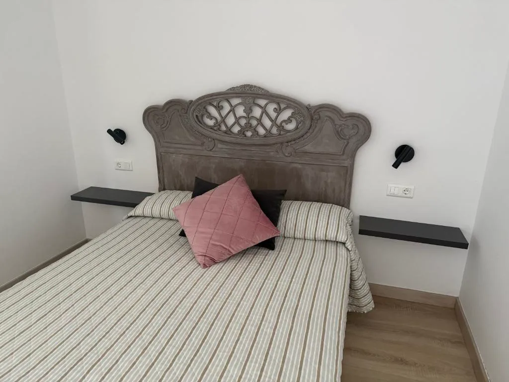 Dormitorio con cabecero tallado en madera y cojín de terciopelo rosa, Hotel Rural VN Tenorio