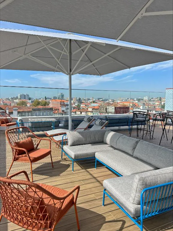 Terraza en la azotea de Wine & Books Porto con sillones de mimbre naranja y vistas al skyline de Oporto