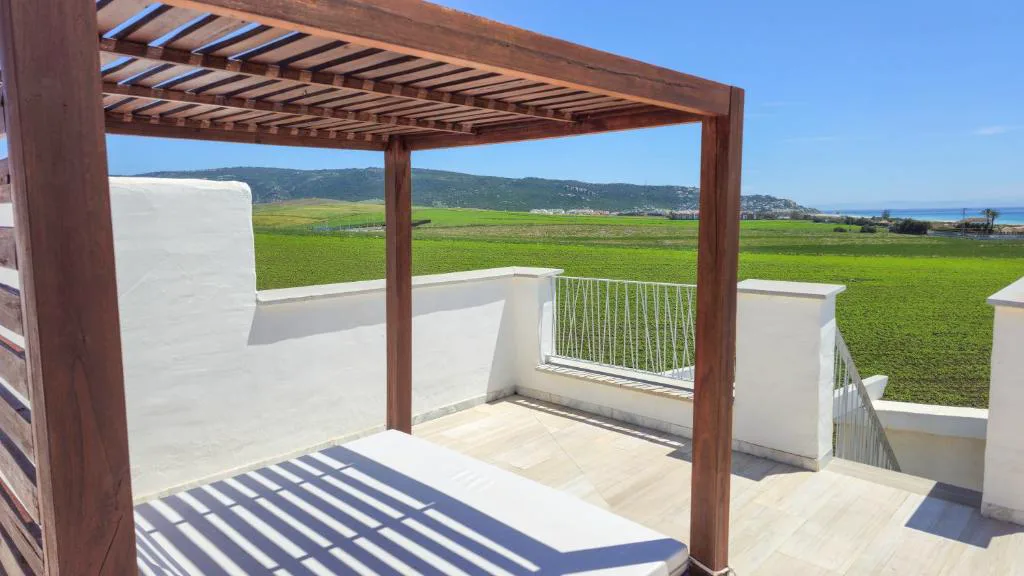 Terraza con pérgola de madera y vistas al campo verde